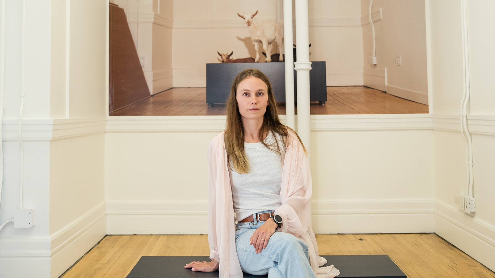 Sage Szkabarnicki-Stuart sitting in front of her photo of baby goats