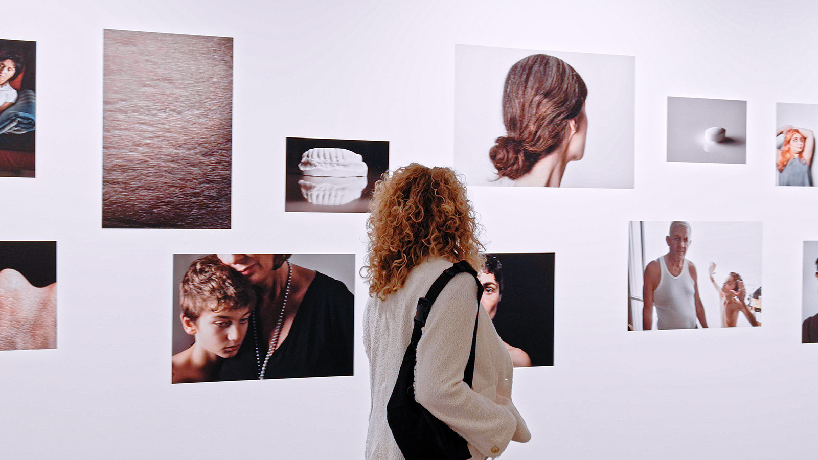 Installation view of Elinor Carucci's photographs, a woman in the foreground looks at the photos